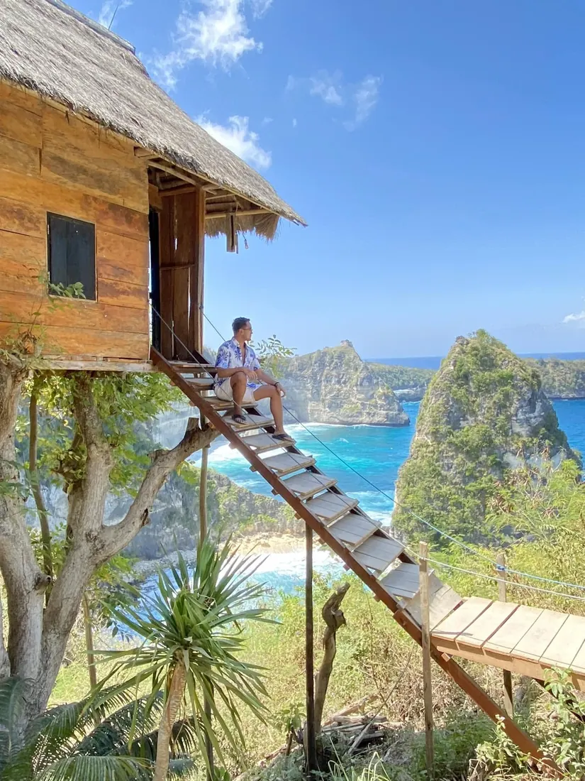 Merald Ayson on a treehouse staircase above seaside cliffs