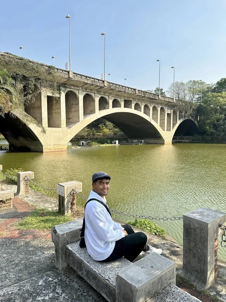 Merald Ayson sitting by a historic arched bridge